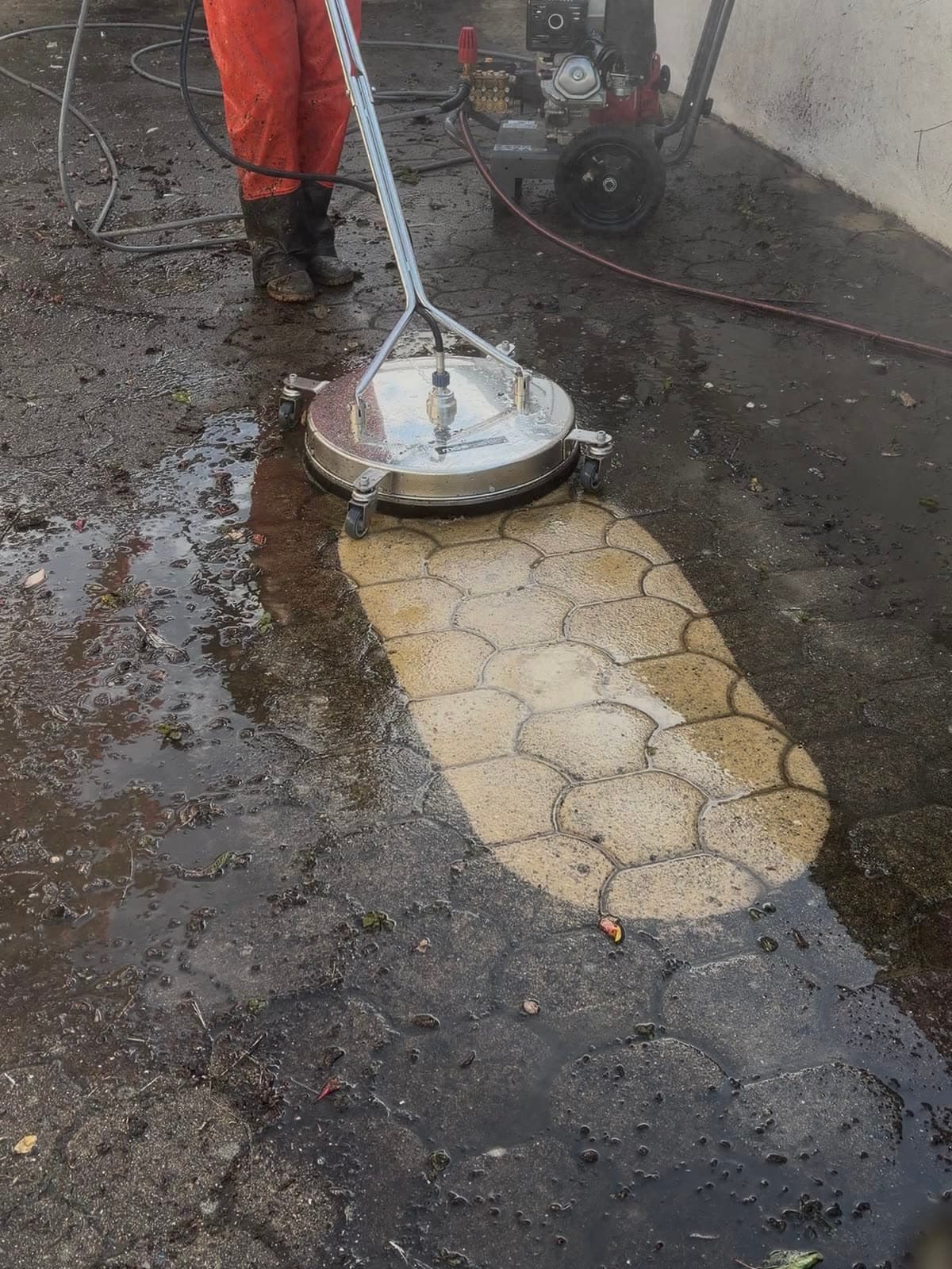 Nettoyeur rotatif haute pression sur une cour en pavés : bande de pavés beiges dégagée au milieu des pavés encore noircis