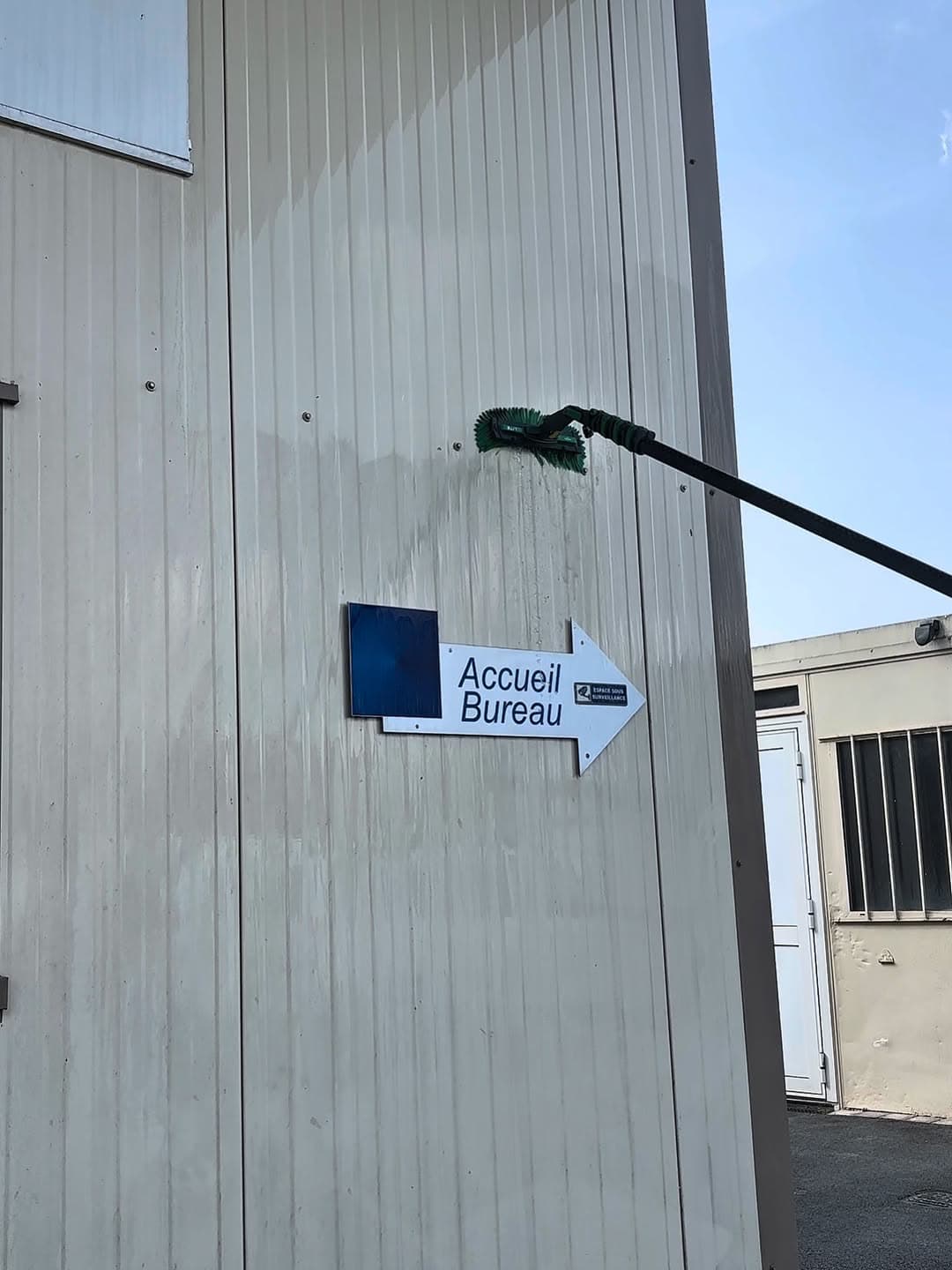 Nettoyage du bardage métallique autour de la signalétique d'une entreprise dans l'Aisne