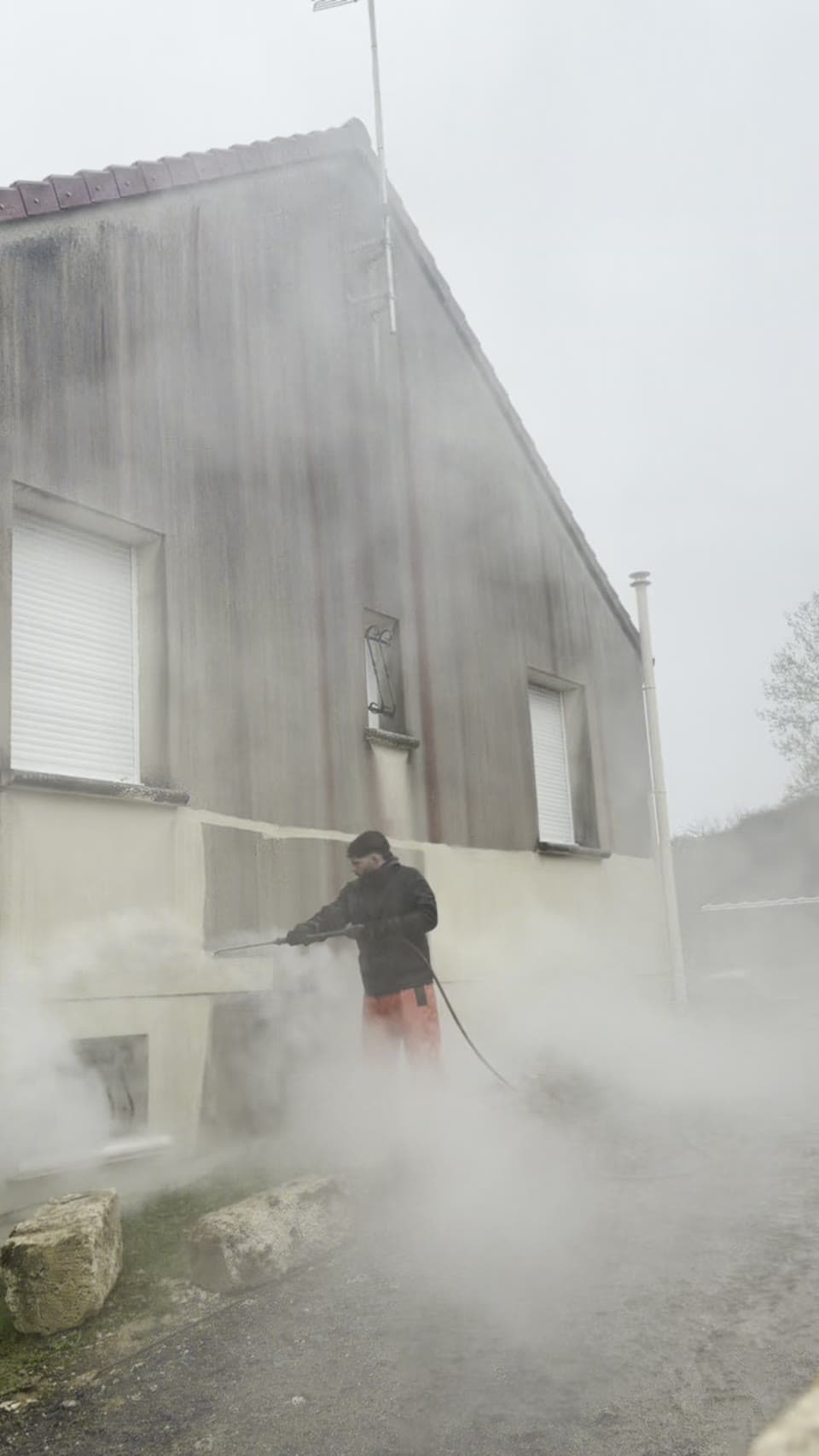 Technicien Mr Cleaning nettoyant la façade enduite d'un bâtiment dans l'Aisne